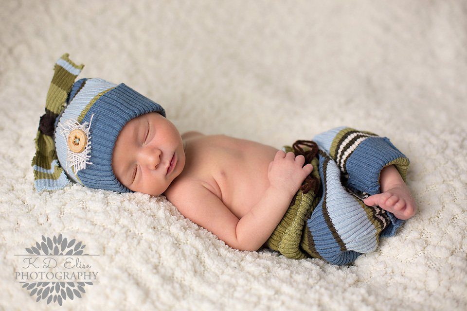Sleeping newborn boy in a blue and green striped outfit. Newborn photography by Pueblo CO Photographer K.D. Elise Photography.