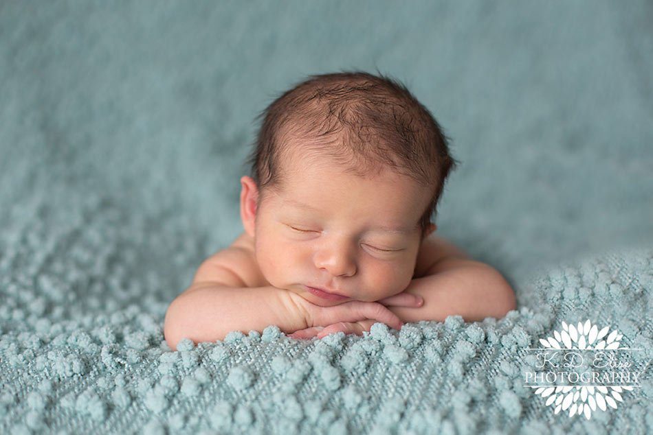 Newborn boy resting his head on his hands while sleeping on a blue blanket. Newborn photography by Pueblo CO photographer.