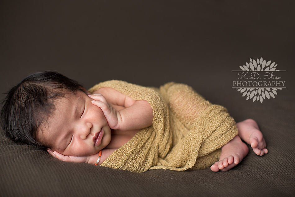 Pueblo, Colorado newborn photography. Sleeping newborn boy wrapped in tan and resting on a green blanket.