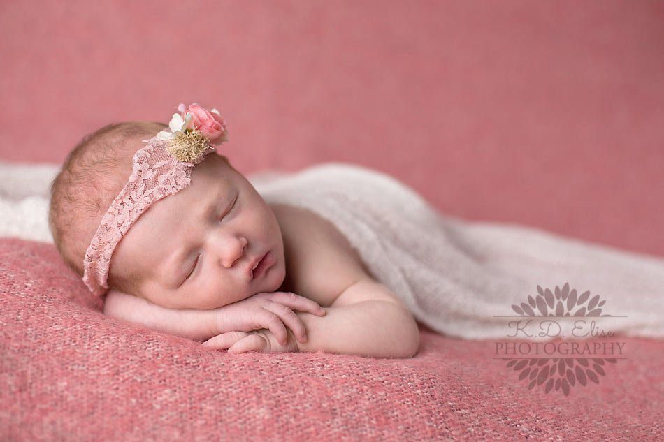 Baby girl sleeps with her arms curled up under her chin during photo session with K.D. Elise Photography, a Pueblo baby photographer