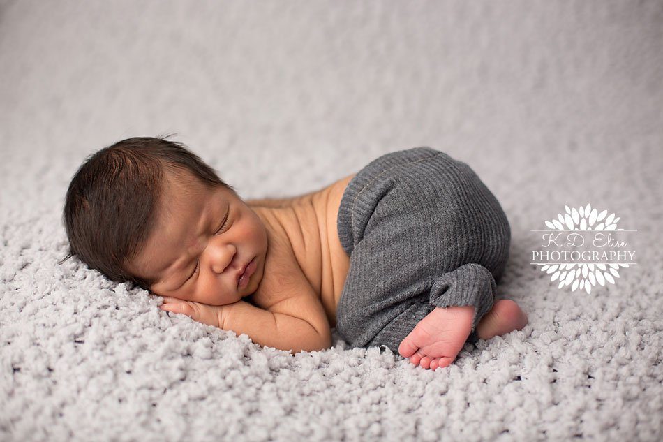 Baby boy in grey pants sleeping on a grey blanket during his newborn session with Colorado Springs newborn photographer K.D. Elise Photography.