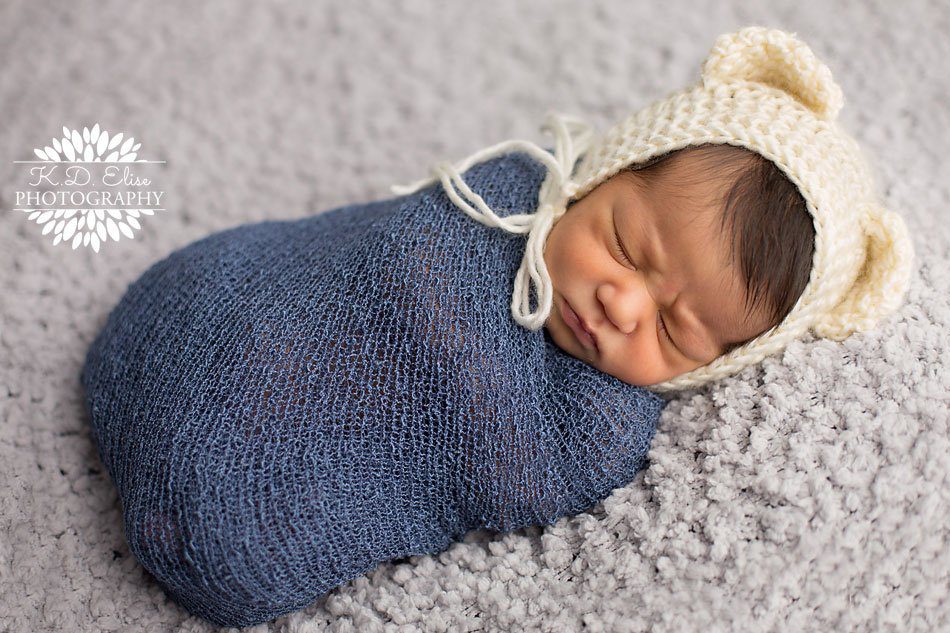 Baby boy in a blue wrap and cream teddy bear bonnet. Newborn photography by Colorado Springs Newborn photographer K.D. Elise Photography.