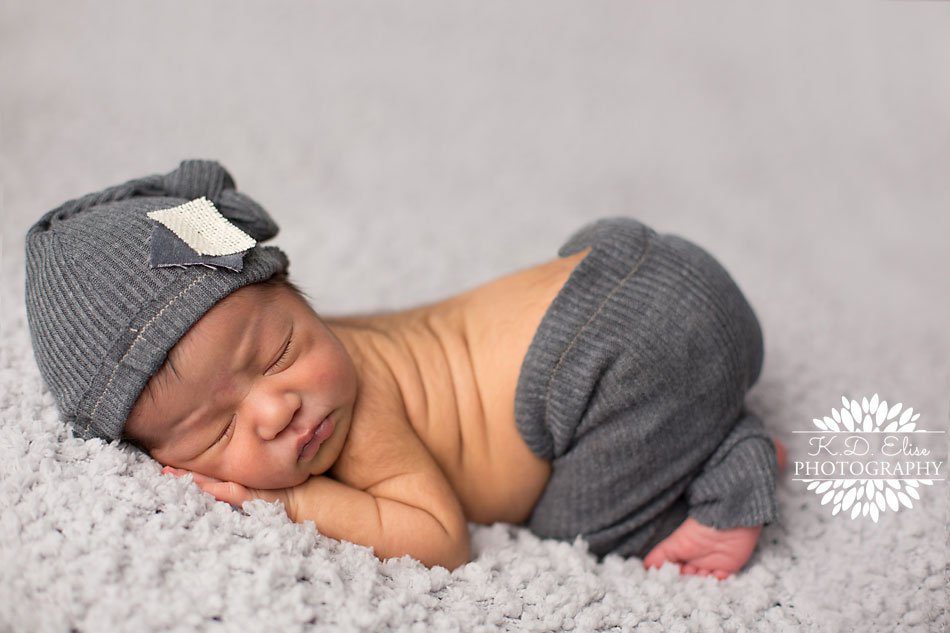 Newborn boy in grey hat and pants outfit, sleeps on his tummy with his bum in the air. Newborn photography by Colorado Springs newborn photographer K.D. Elise Photography.
