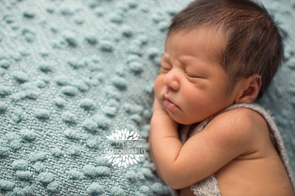 Side profile photo of a newborn baby boy laying on a blue blanket. Custom newborn photography by Colorado Springs newborn photographer K.D. Elise Photography.