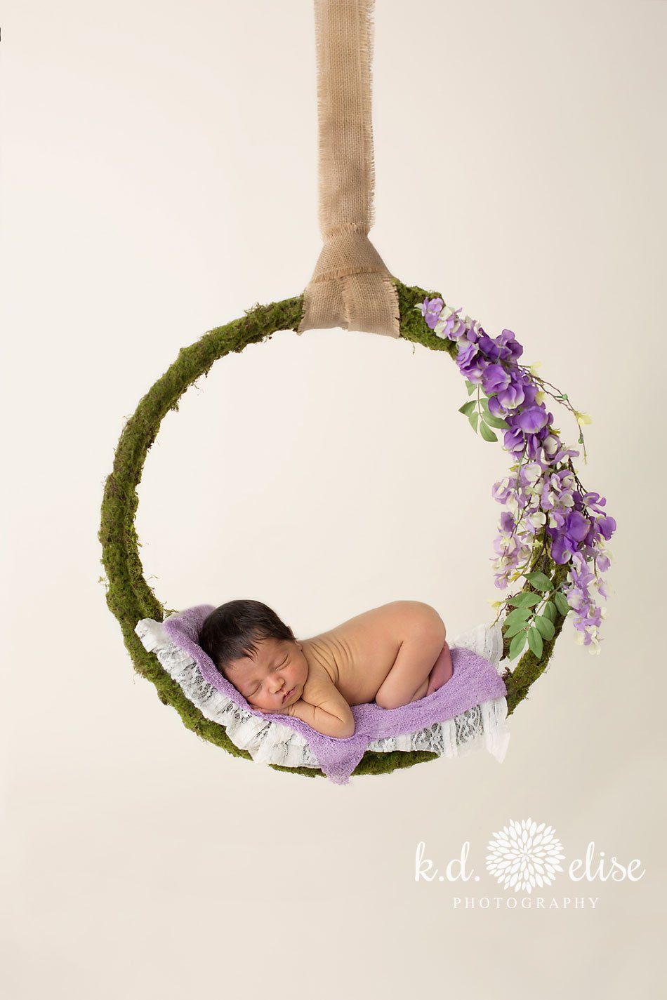 Newborn baby girl hanging in a floral wreath by Colorado Springs newborn photographer K.D. Elise Photography.