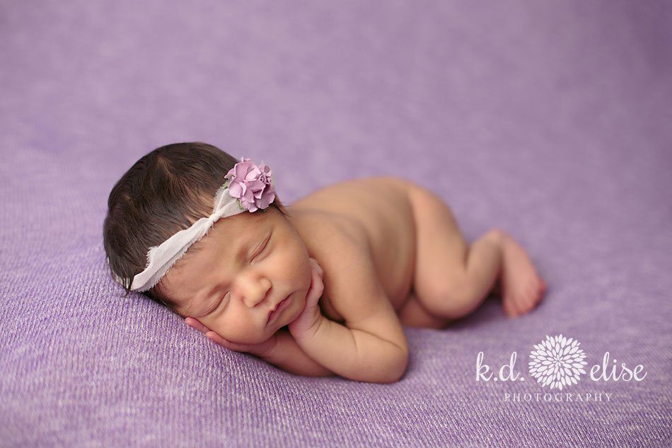 Baby girl laying on her side on a purple blanket by Colorado Springs newborn photographer K.D. Elise Photography.