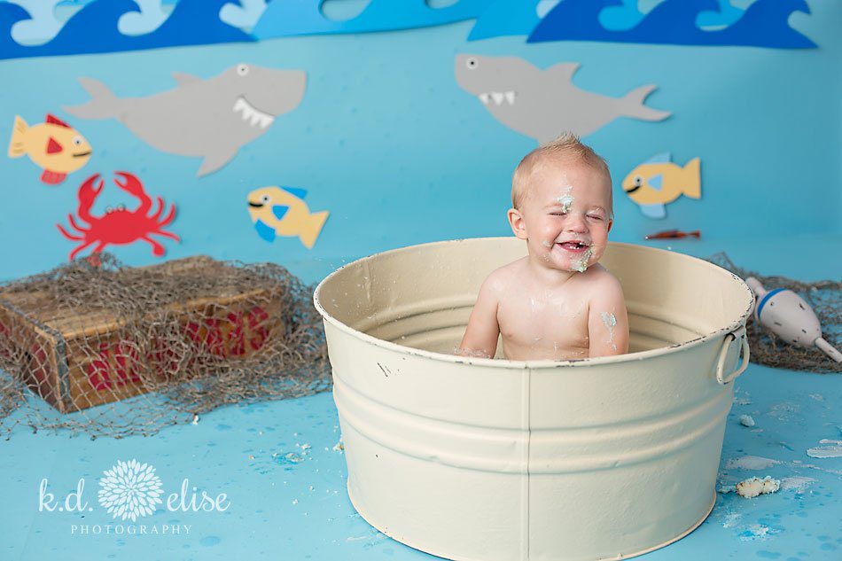 Happy smiling little boy taking a bath after his first birthday cake smash.