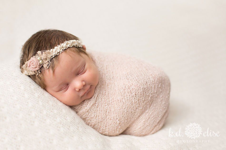 Smiling newborn baby girl by Colorado Springs newborn photographer K.D. Elise Photography.