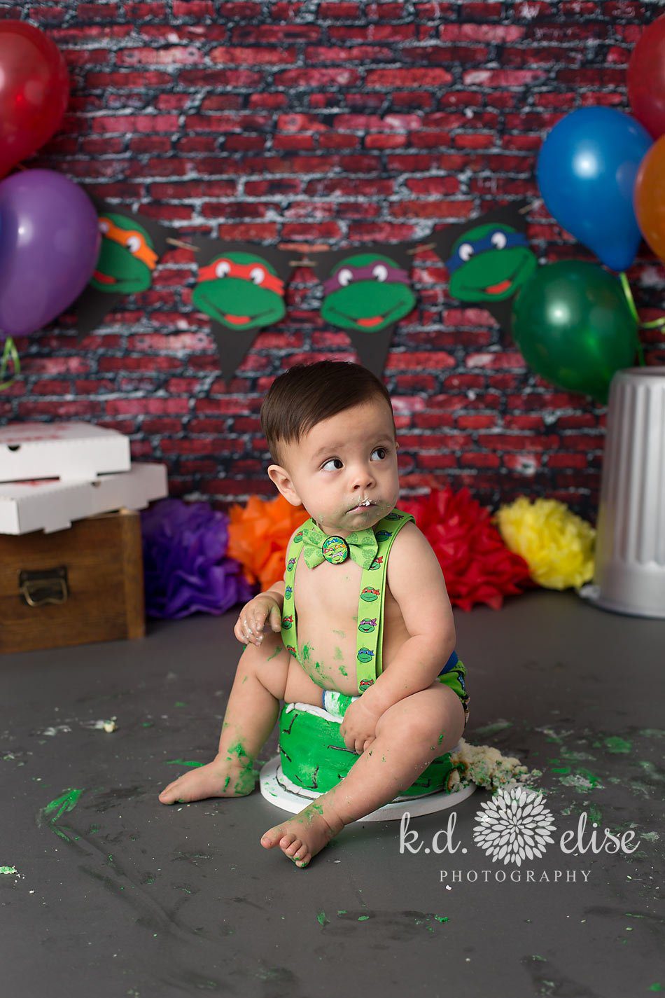 Baby boy sitting on birthday cake during cake smash.