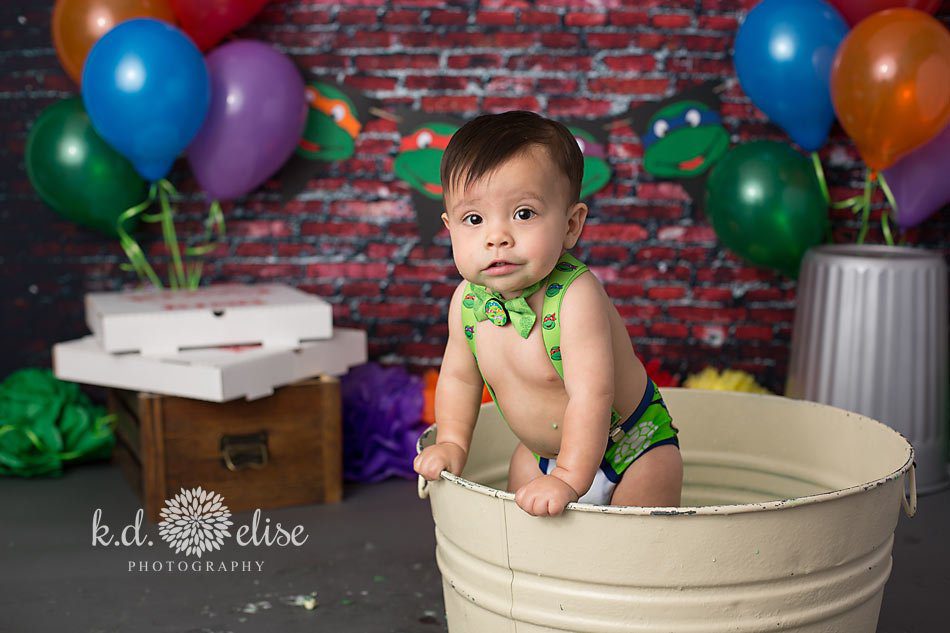 Baby boy in a metal bathtub, cleaning up from cake smash.