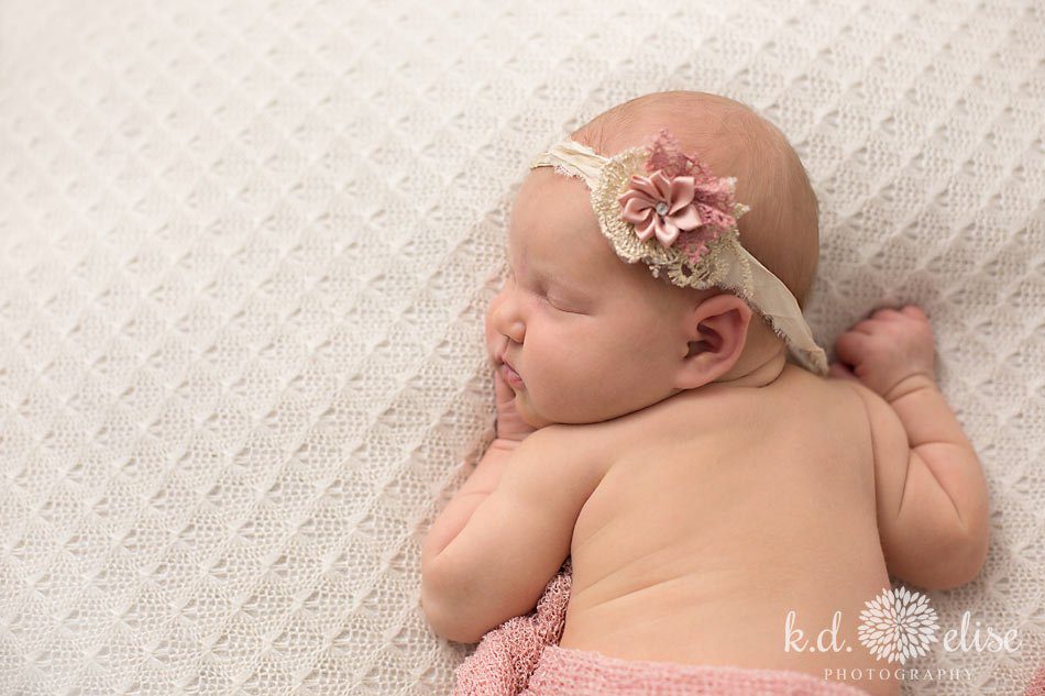 Newborn baby girl wearing pink flower headband.