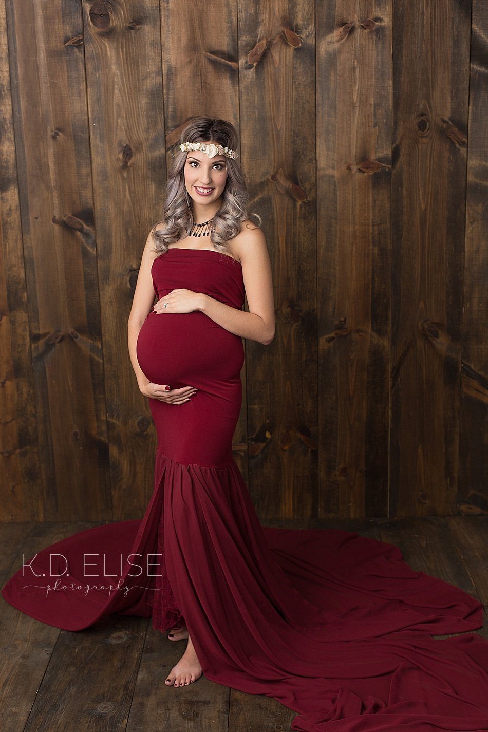 Pregnant mom in red gown looking at the camera. Maternity portraits by Pueblo maternity photographer K.D. Elise Photography.