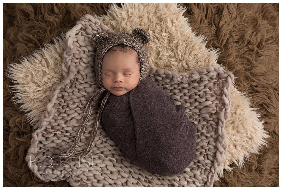 Newborn baby boy in a bear bonnet, laying on brown fur. By Colorado Springs and Pueblo newborn photographer.