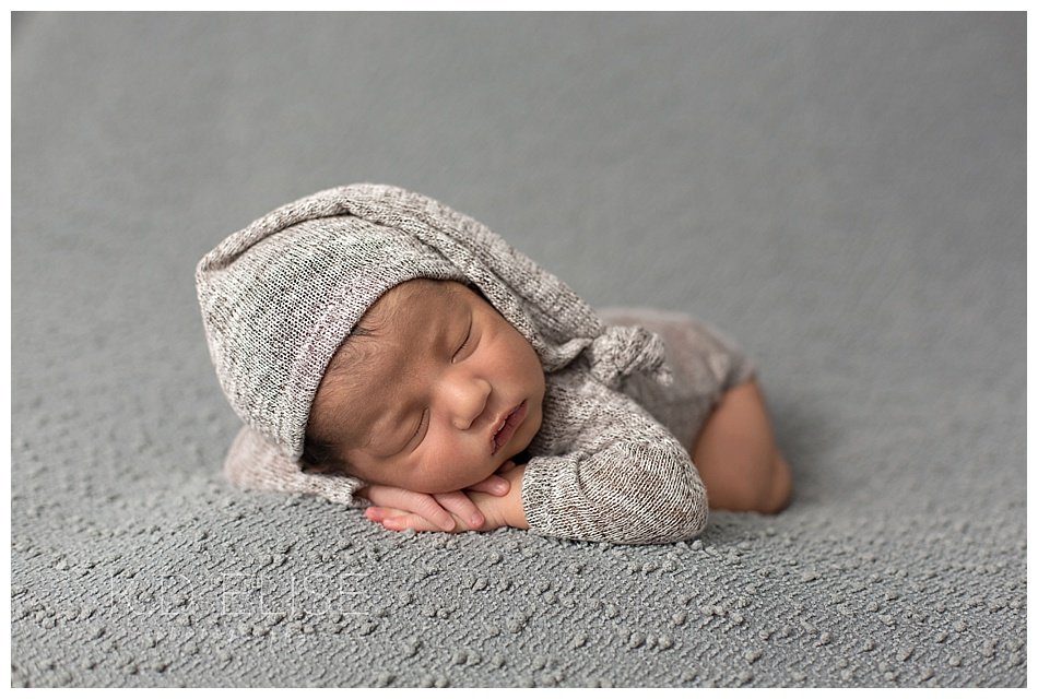 Newborn baby photos of sleeping boy in long tailed cap.
