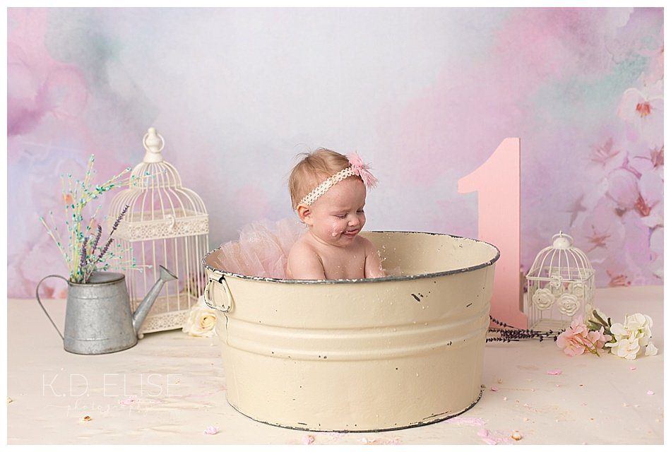 One year old girl in metal wash basin after cake smash with K.D. Elise Photography.