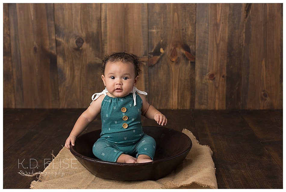Six month baby photos of little boy sitting in a wooden bowl.