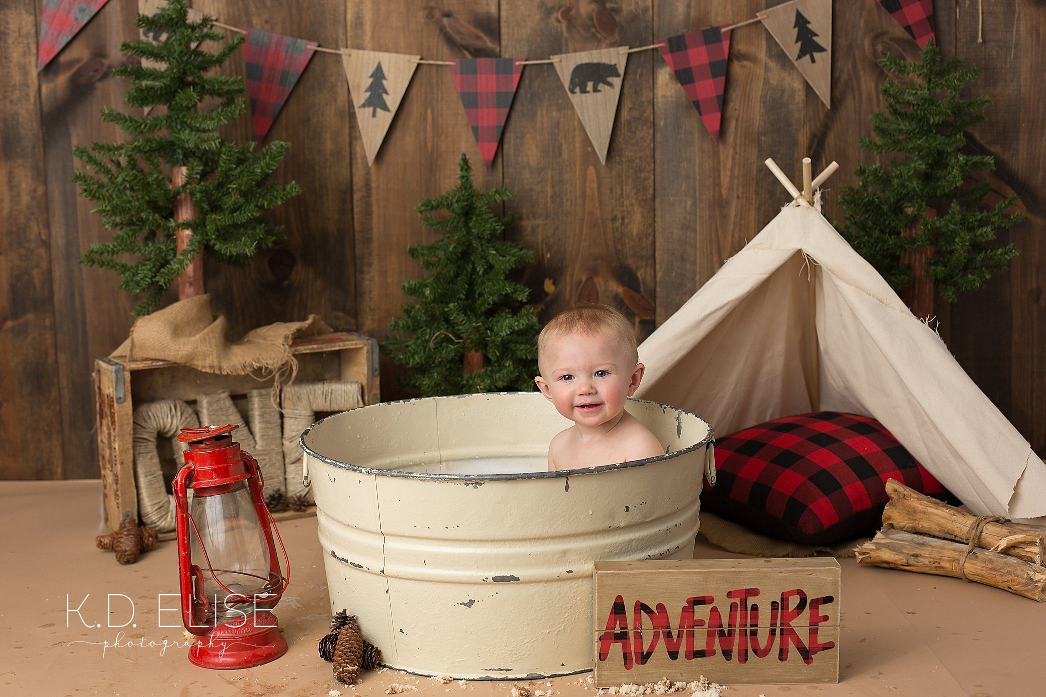 Baby in a bathtub after his first birthday cake smash with K.D. Elise Photography, featuring a fun lumberjack theme.