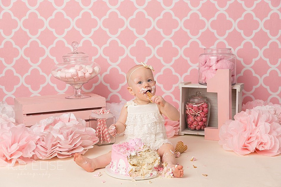 Baby girl taking a bite of cake during candy themed cake smash with K.D. Elise Photography, a photographer in Pueblo, CO.