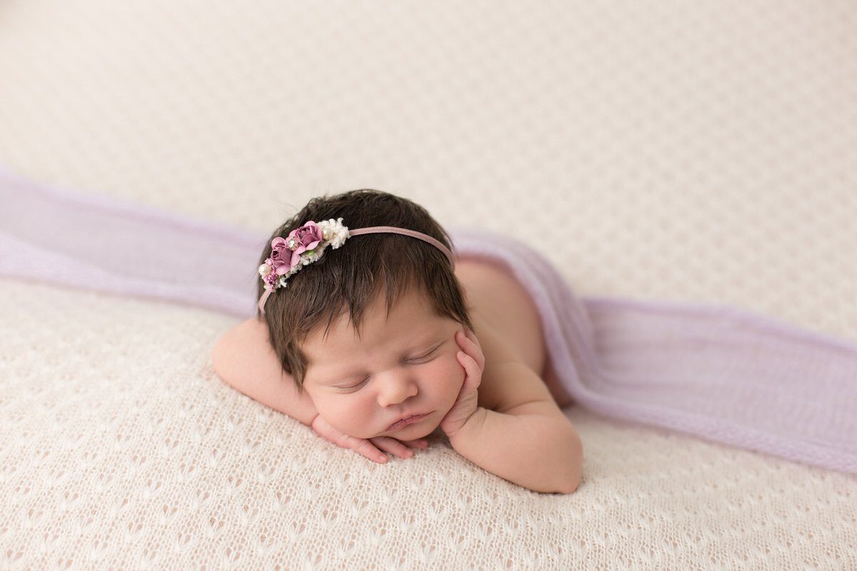 Sleeping baby girl in purple on a cream backdrop by Pueblo Colorado Springs newborn photographer K.D. Elise Photography.