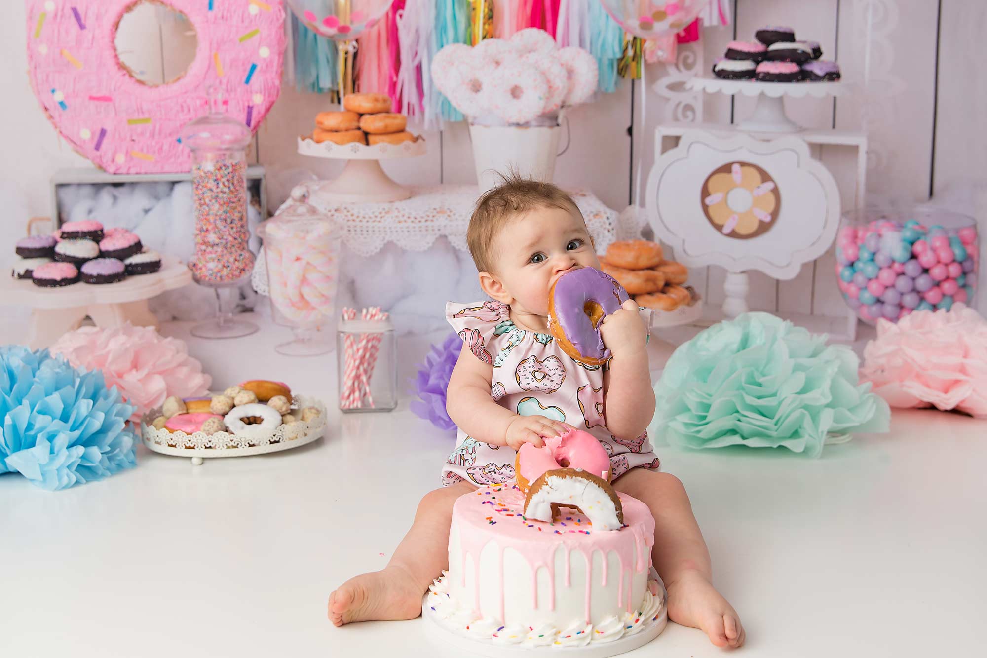 Baby girl eating a donut during donut themed cake smash by Pueblo photographer K.D. Elise Photography.