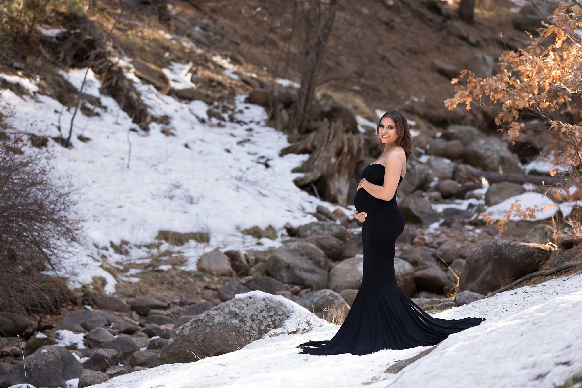 Pregnant mom in black dress standing in the snow. Maternity session by Pueblo photographer K.D. Elise Photography.