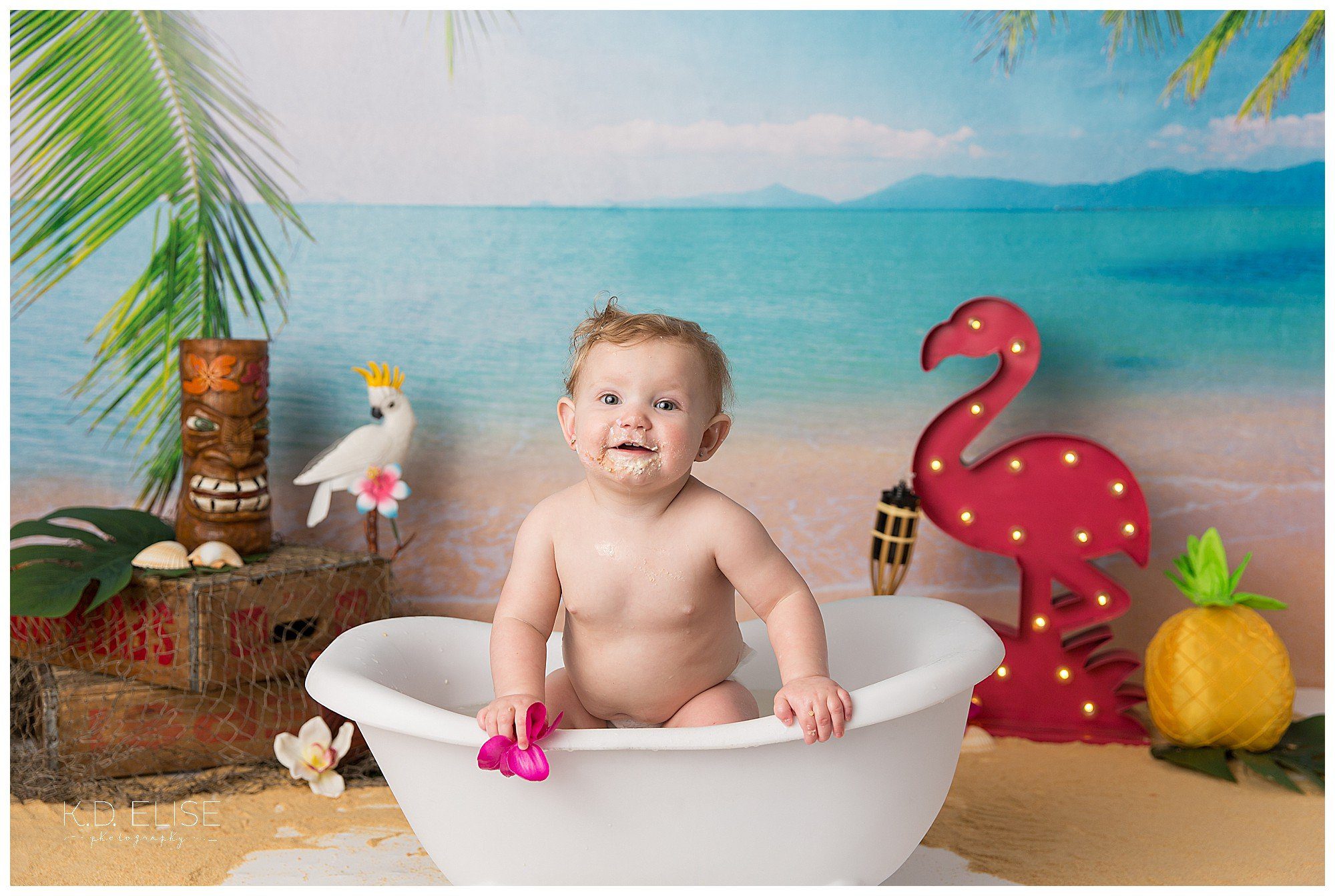 Baby girl in bathtub after luau themed cake smash from K.D. Elise Photography.