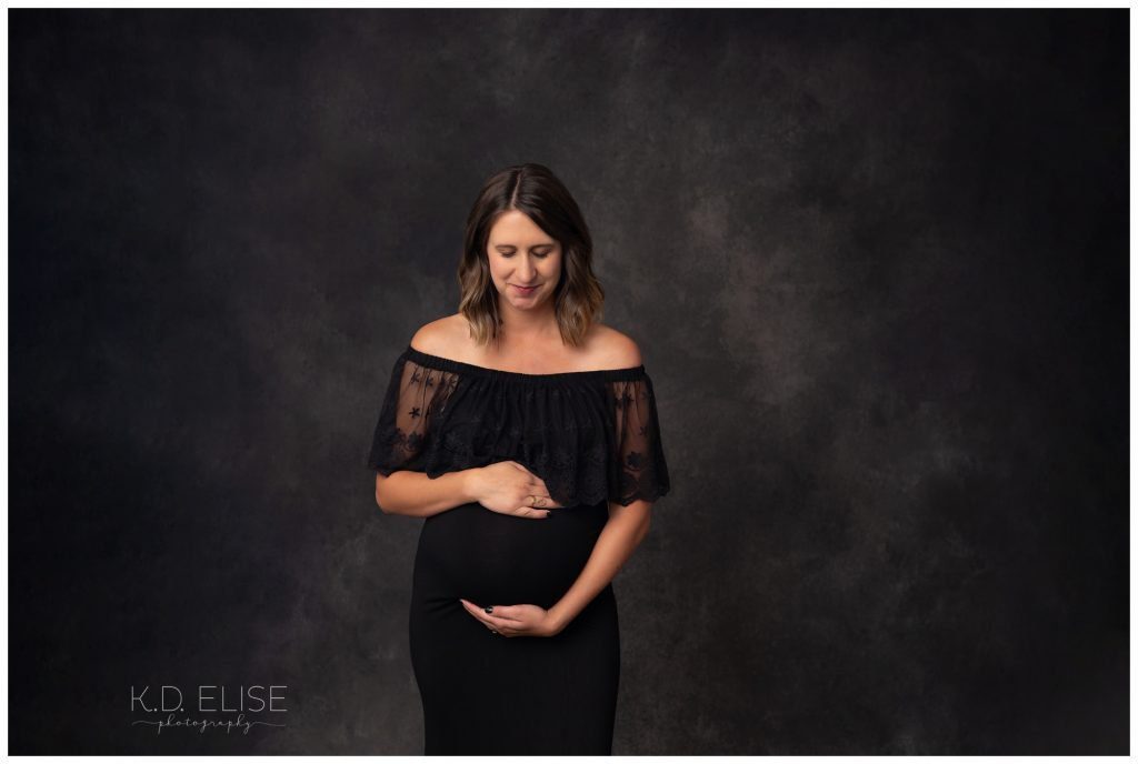 In studio maternity photography image of pregnant mom in black gown.